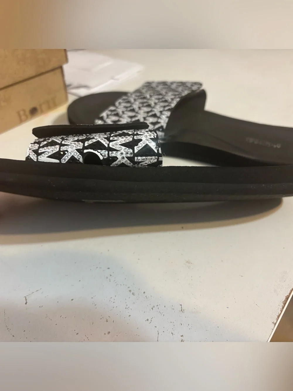 Michael Kors black & white slides featuring a signature logo print on the strap.